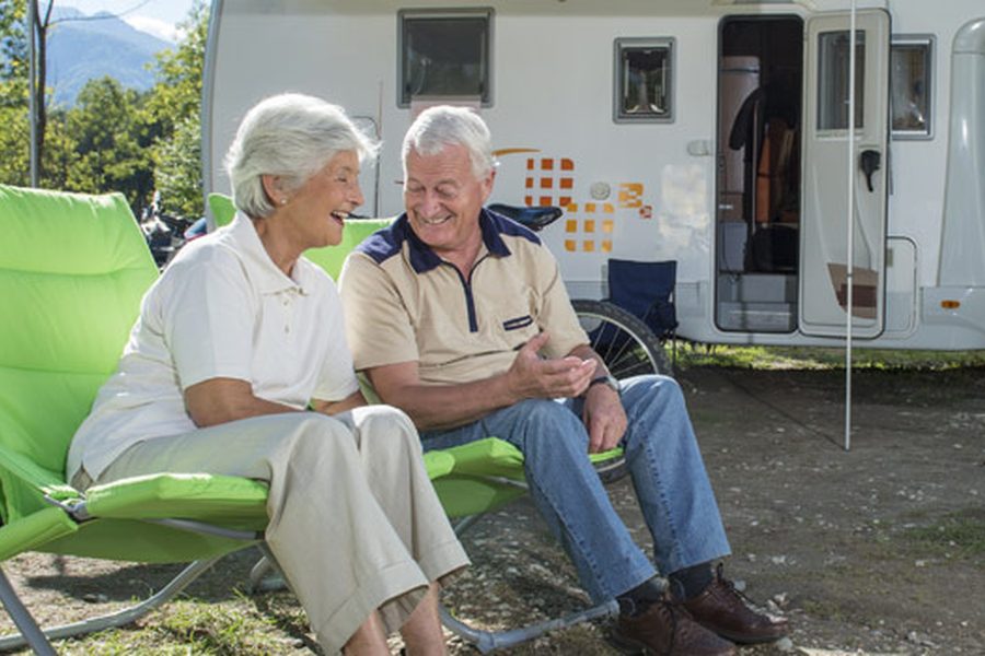 Retired couple relaxing by their caravan